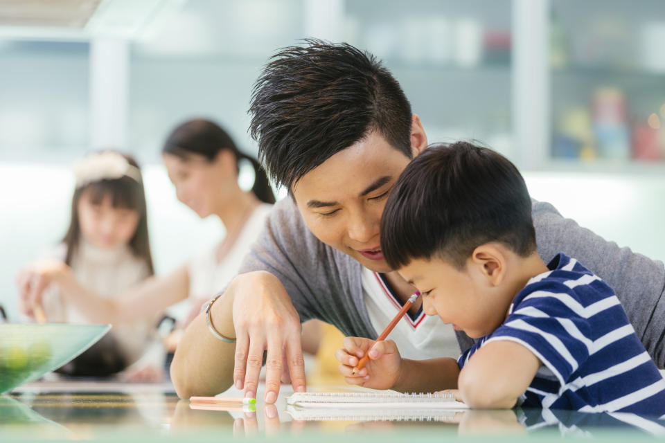 A Chinese family works on schoolwork in their kitchen.