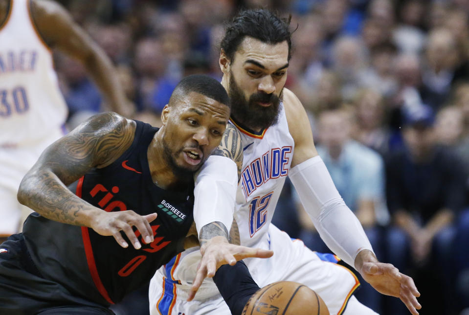 Portland Trail Blazers guard Damian Lillard (0) and Oklahoma City Thunder center Steven Adams (12) reach for the ball in the first half of an NBA basketball game in Oklahoma City, Monday, Feb. 11, 2019. (AP Photo/Sue Ogrocki)