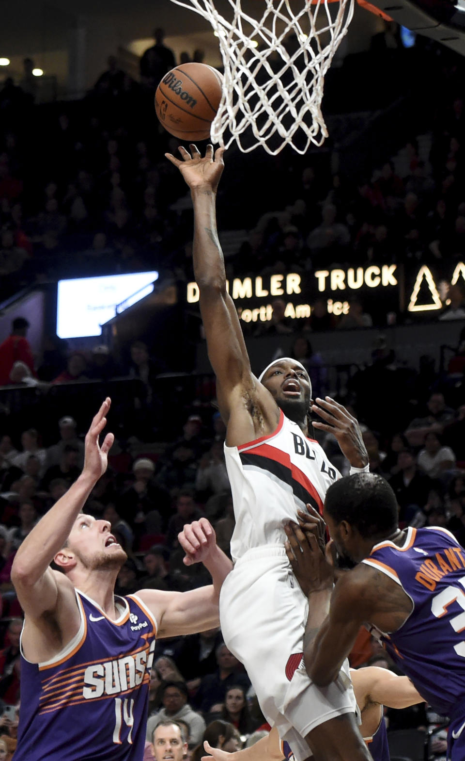 Portland Trail Blazers forward Jerami Grant, center, hits a shot over Phoenix Suns forward Drew Eubanks, left, and forward Kevin Durant, right, during the second half of an NBA basketball game in Portland, Ore., Tuesday, Dec. 19, 2023. The Blazers won 109-104. (AP Photo/Steve Dykes)