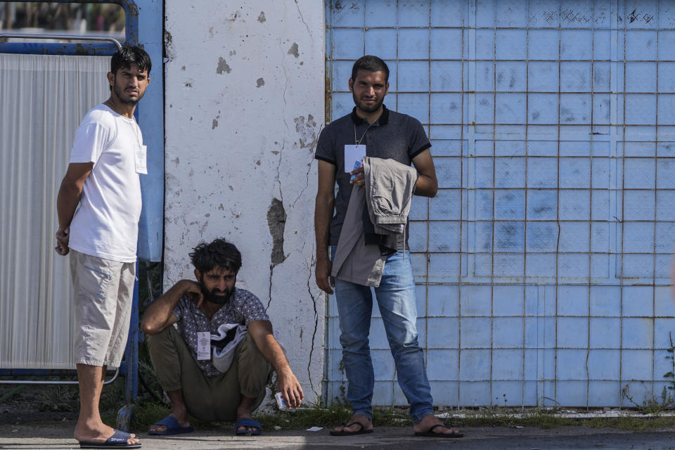 Survivors of a shipwreck stand outside a warehouse at the port in Kalamata town, about 240 kilometers (150miles) southwest of Athens, Greece, Thursday, June 15, 2023. A fishing boat crammed to the gunwales with migrants trying to reach Europe capsized and sank Wednesday June 14 off the coast of Greece, authorities said, leaving at least 79 dead and many more missing in one of the worst disasters of its kind this year. (AP Photos/Thanassis Stavrakis)