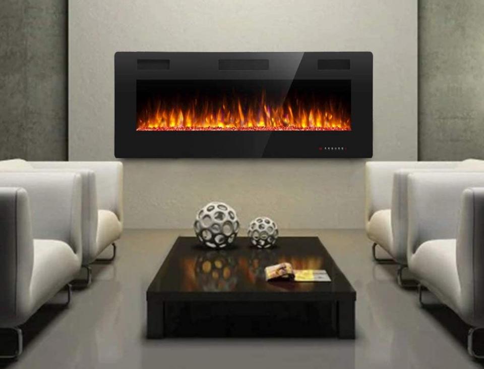 An electric fireplace burning brightly in a modern, cold, grey living area with four chairs.