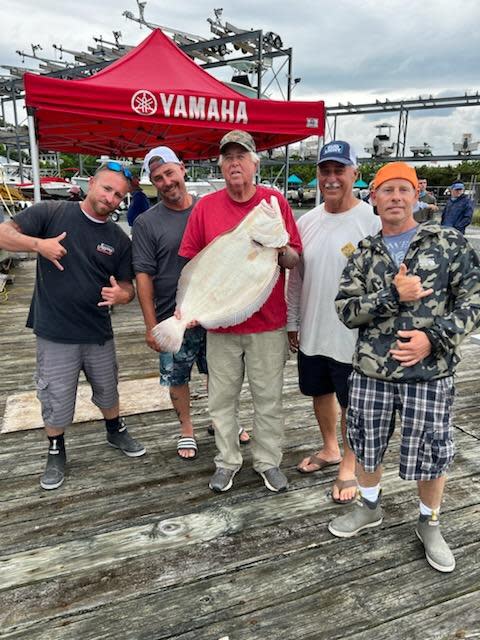 Ted Gaydos, center, of Monroe Township, holds the 12.4-pound fluke he landed, which one him the grand prize of $50,000 cash in the Jersey Coast Angler's Association's 26th annual fluke contest.