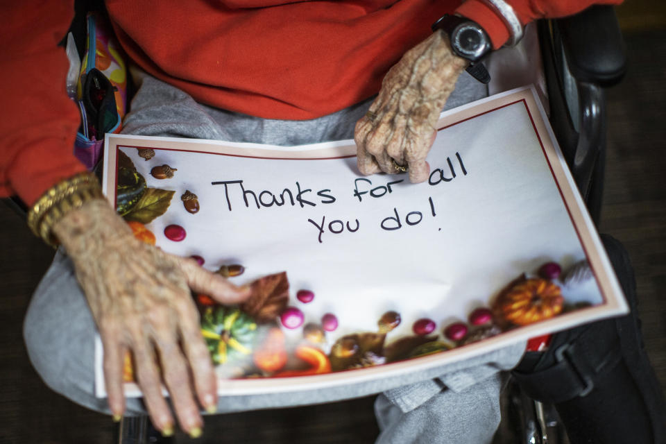 A nursing home resident holds a sign addressed to the staff before a small Thanksgiving Day parade with nurses, other staff and residents at the Hebrew home at Riverdale in the Bronx, Thursday, Nov 26, 2020, in New York.(AP Photo/Eduardo Munoz Alvarez)