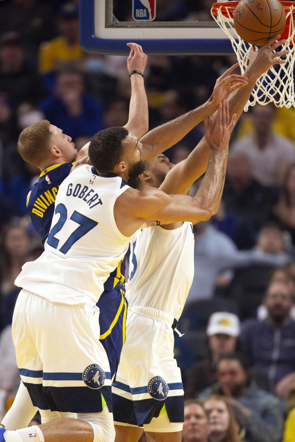 Golden State Warriors guard Donte DiVincenzo, from left, Minnesota Timberwolves defenders Rudy Gobert (27) and Kyle Anderson vie for a rebound during the first quarter of an NBA basketball game, Sunday, March 26, 2023, in San Francisco. (AP Photo/D. Ross Cameron)