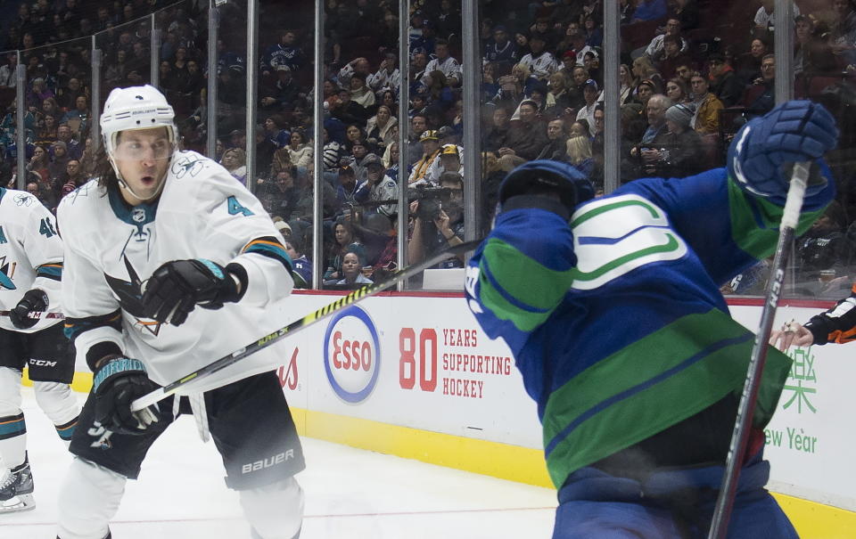 San Jose Sharks defenseman Brenden Dillon (4) high-sticks Vancouver Canucks right wing Jake Virtanen during the second period of an NHL hockey game Saturday, Jan. 18, 2020, in Vancouver, British Columbia. (Jonathan Hayward/The Canadian Press via AP)