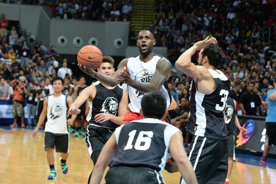 US NBA superstar LeBron James (C) plays during an exhibition game as part of a clinic session in Manila on August 20, 2015. James is here to conduct basketball clinic to select talented baskeball players from disadvantaged families.    AFP PHOTO / TED ALJIBE        (Photo credit should read TED ALJIBE/AFP/Getty Images)