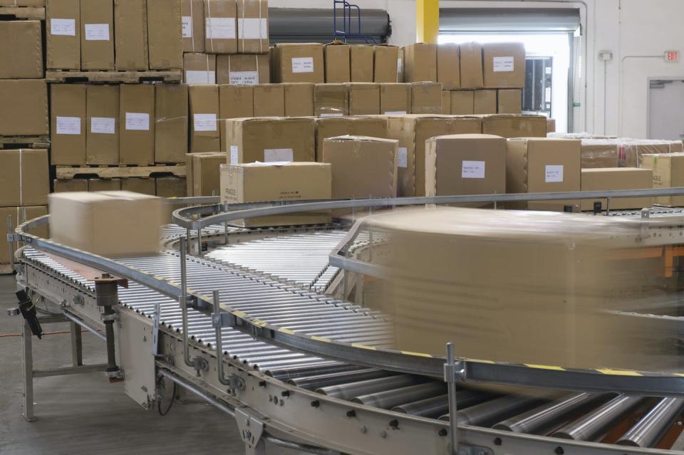 Les entrepôts de vente au détail sont souvent de vastes bâtiments équipés de tapis roulants et de piles de produits et de matériaux d’emballage. <a href="https://www.shutterstock.com/fr/image-photo/cardboard-boxes-on-conveyor-belt-distribution-148488479" rel="nofollow noopener" target="_blank" data-ylk="slk:Shutterstock;elm:context_link;itc:0;sec:content-canvas" class="link ">Shutterstock</a>