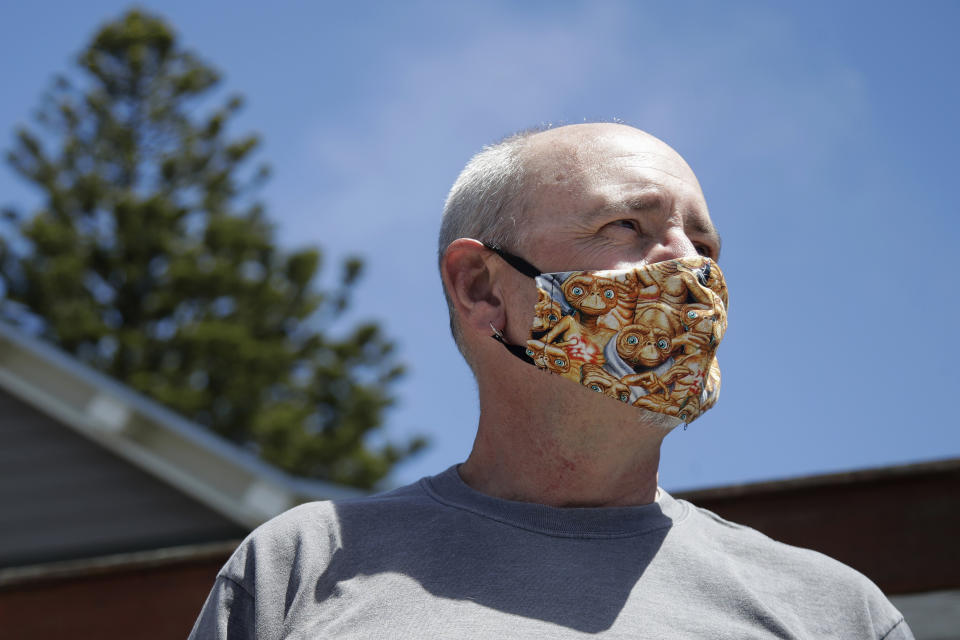 Tom Hicks, a furloughed employee from Luminalt Solar Energy Solutions, wears a face mask as he poses for a portrait in San Francisco, Tuesday, April 28, 2020. Luminalt is paying for Hicks' health benefits, though he is not getting a salary. A future that looked bright for the renewable energy industry has clouded as the coronavirus batters the world economy. (AP Photo/Jeff Chiu)