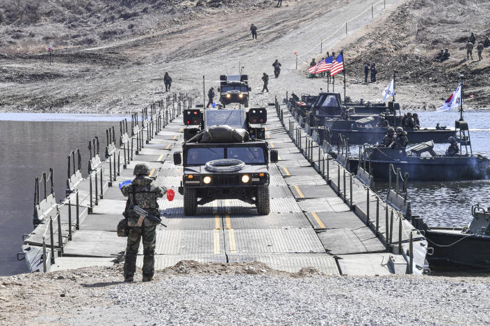 In this photo provided by South Korea Defense Ministry, U.S. military vehicles cross a river as South Korean soldiers gives a signal during a joint river-crossing drill between South Korea and the United States in Yeoncheon, South Korea, Monday, March 13, 2023. (South Korea Defense Ministry via AP)