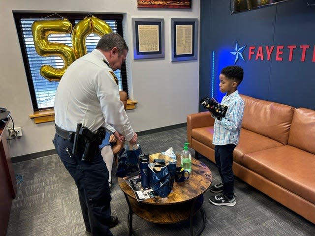 Fayetteville Police Chief Kemberle Braden prepares to hand a gift bag to Phillip Baldwin after he and his sister Roslyn, 14, visited the Police Department from Louisiana on Friday, Jan. 26, 2024, in their mission to hug police officers in all 50 states.