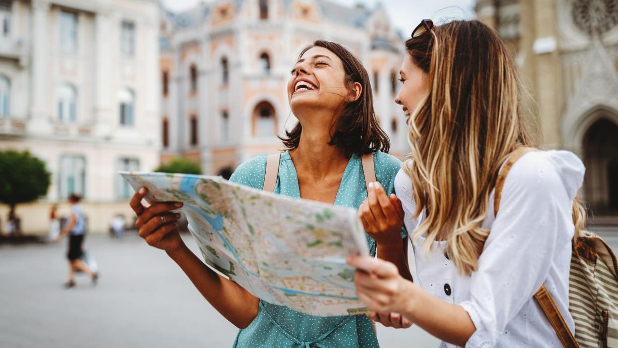 dos amigas sonrientes haciendo turismo en vacaciones, con un mapa en la mano