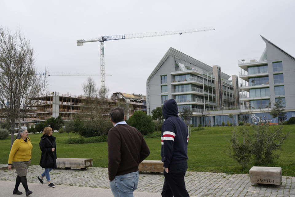 People walking along the Tagus river look at new luxury buildings in Lisbon, Friday, March 10, 2023. Portugal’s center-left Socialist government is set to approve a package of measures to address the country's housing crisis. A growing number of people are being priced out of the property market by rising rents, surging house prices and climbing mortgage rates. (AP Photo/Armando Franca)