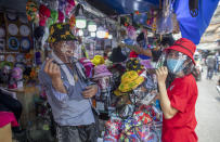 A woman tryout a hat with face shield at a street vender in Bangkok, Thailand, Thursday, April 2, 2020. The new coronavirus causes mild or moderate symptoms for most people, but for some, especially older adults and people with existing health problems, it can cause more severe illness or death. (AP Photo/Gemunu Amarasinghe)