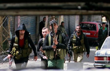 Members of the Palestinian Fatah faction walk with their weapons as seen through a damaged car inside the Ain el-Hilweh refugee camp near Sidon, southern Lebanon April 11, 2017. REUTERS/Ali Hashisho