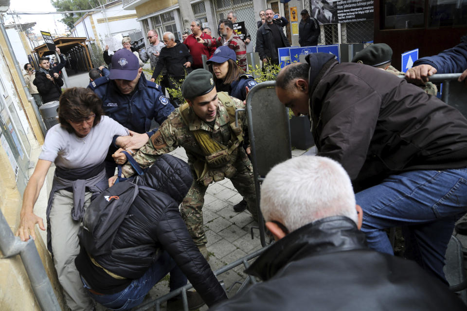 Protesters break the barriers as they demonstrate against the closing of a crossing point straddling a United Nations-controlled buffer zone in divided capital Nicosia, Cyprus, Saturday, Feb. 29, 2020. Around 200 people gathered at the Ledra Street crossing point to voice their opposition to its closing. The Cyprus government said it closed the Ledra Street crossing point along with three others to help with efforts to prevent the possible spread of a new COVID-19 virus either to the breakaway, Turkish Cypriot north or the internationally recognized, Greek Cypriot south. (AP Photo/Petros Karadjias)