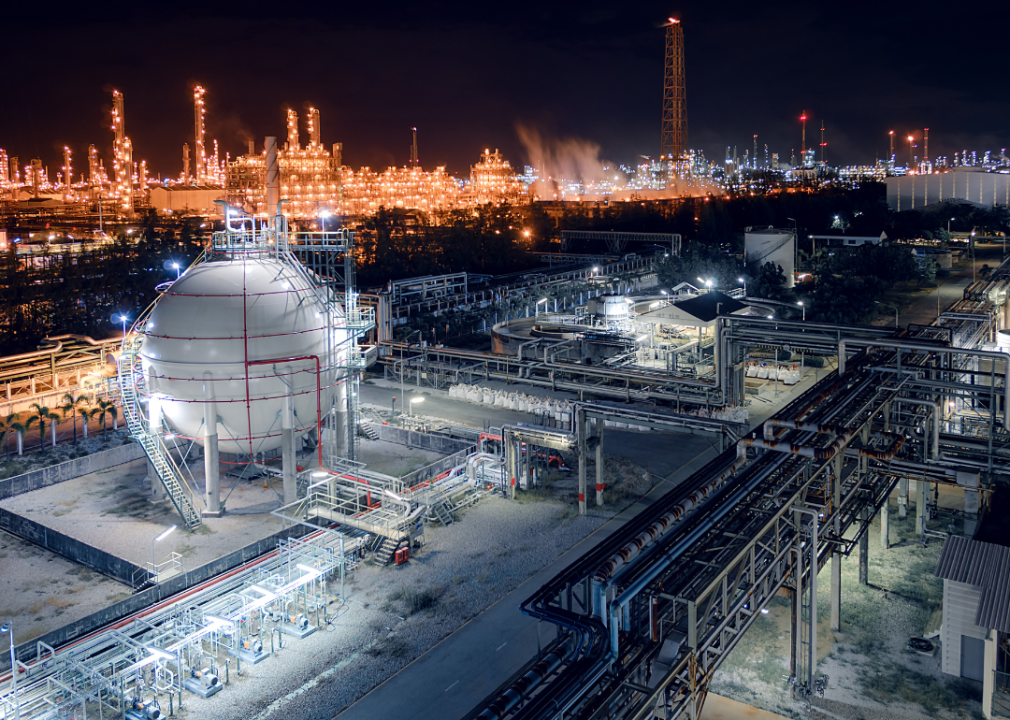 Large pertoleum facility with a vast number of pipes lit at night.