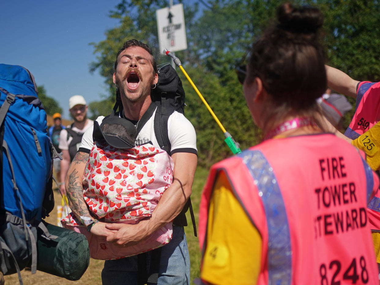 A festivalgoer is sprayed with water by a steward on the first day of the Glastonbury Festival at Worthy Farm in Somerset. Picture date: Wednesday June 22, 2022.