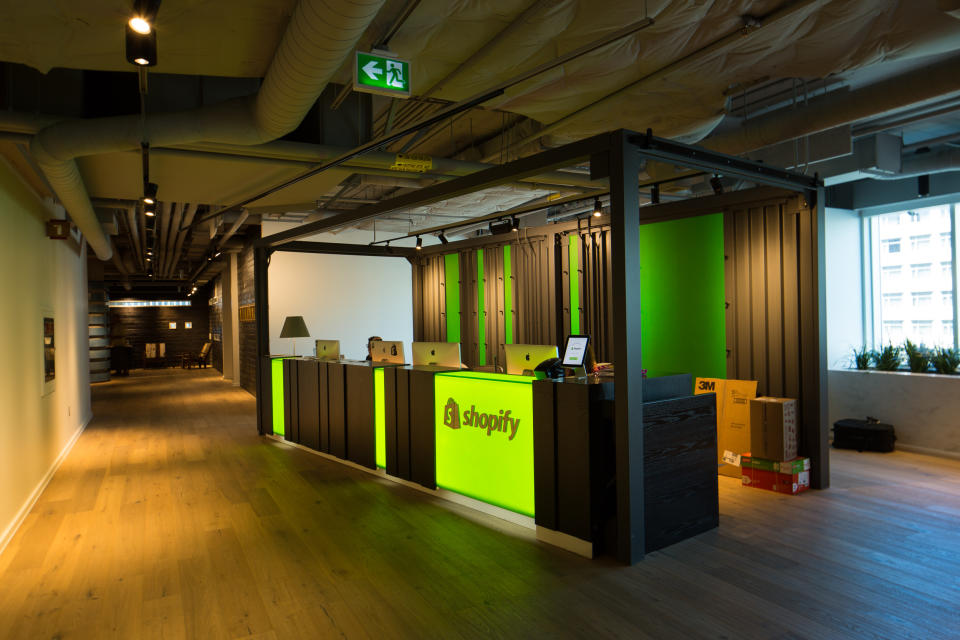 The lobby of Shopify HQ in Ottawa with an illuminated Shopify logo on the front of a desk.