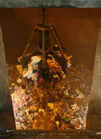 A mechanical claw operated by a worker lifts a pile of waste to be transferred to an incinerator at the Tuas South incineration plant in Singapore April 21, 2008. The plant incinerates waste into ash, which is then transported to Semakau Island and deposited into a landfill. REUTERS/Vivek Prakash