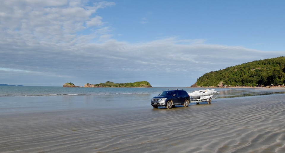 A 4WD towing a boat and trailer on the beach at Cape Hillsborough in Mackay.