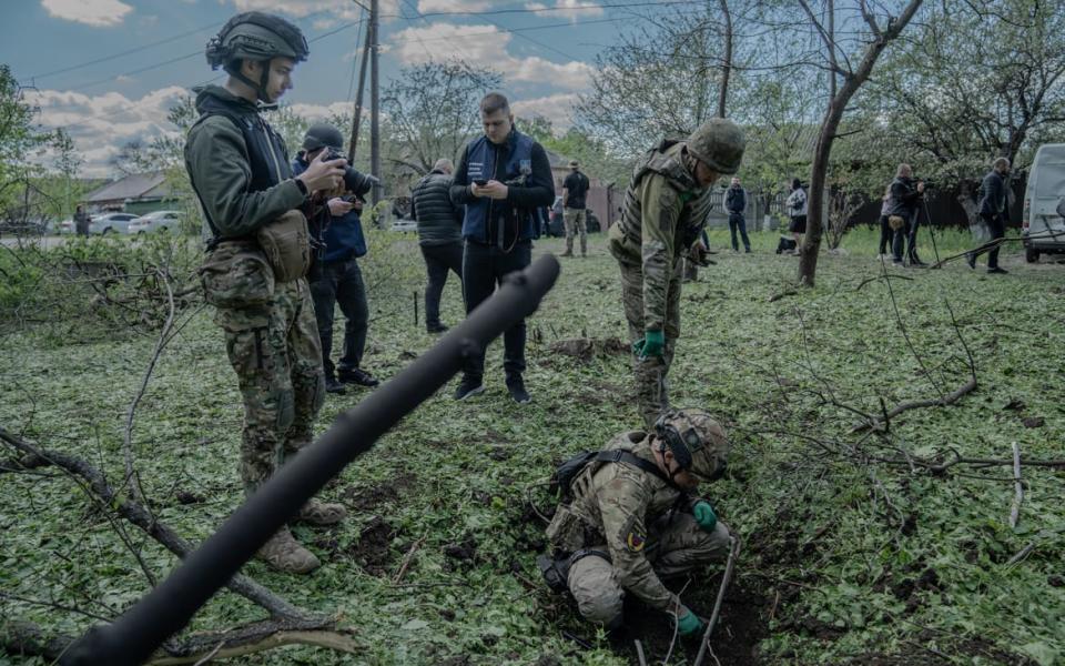 A military expert surveys a bomb crater at the site of a Russian aerial bombing of the city's Saltivskyi district.