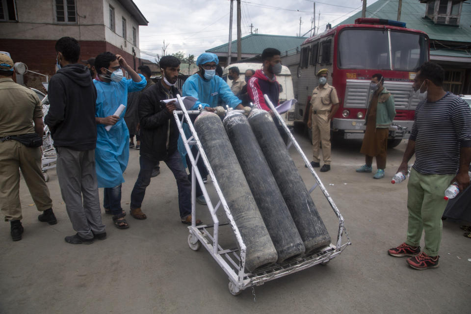 Local men hired by administration assist transport of oxygen cylinders in the premises of a hospital in Srinagar, Indian controlled Kashmir, Sunday, May 23, 2021. (AP Photo/Mukhtar Khan)