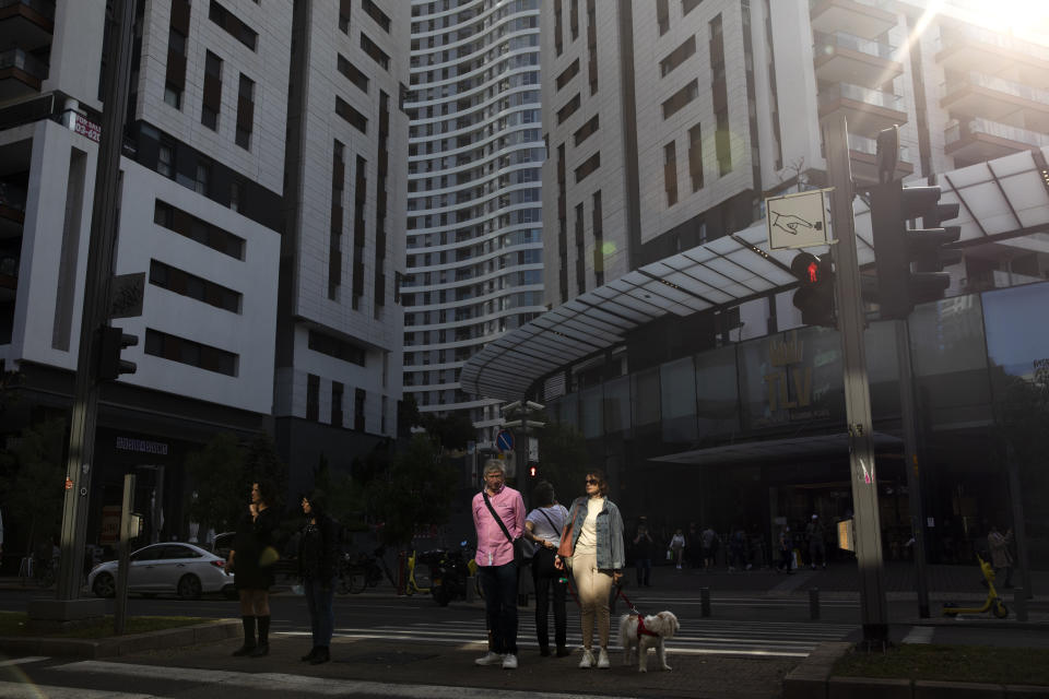 People cross a road next to a residential and commercial project in Tel Aviv, Israel, Thursday, Dec. 2, 2021. Residents of Israel's seaside metropolis Tel Aviv have for years complained of how expensive it is, with living costs taking a chunk out of their paychecks. A report released Wednesday, Dec. 1, 2021, by the Economist Intelligence Unit, a research group linked to the Economist magazine, said Tel Aviv has emerged as the most expensive city to live in. (AP Photo/Oded Balilty)