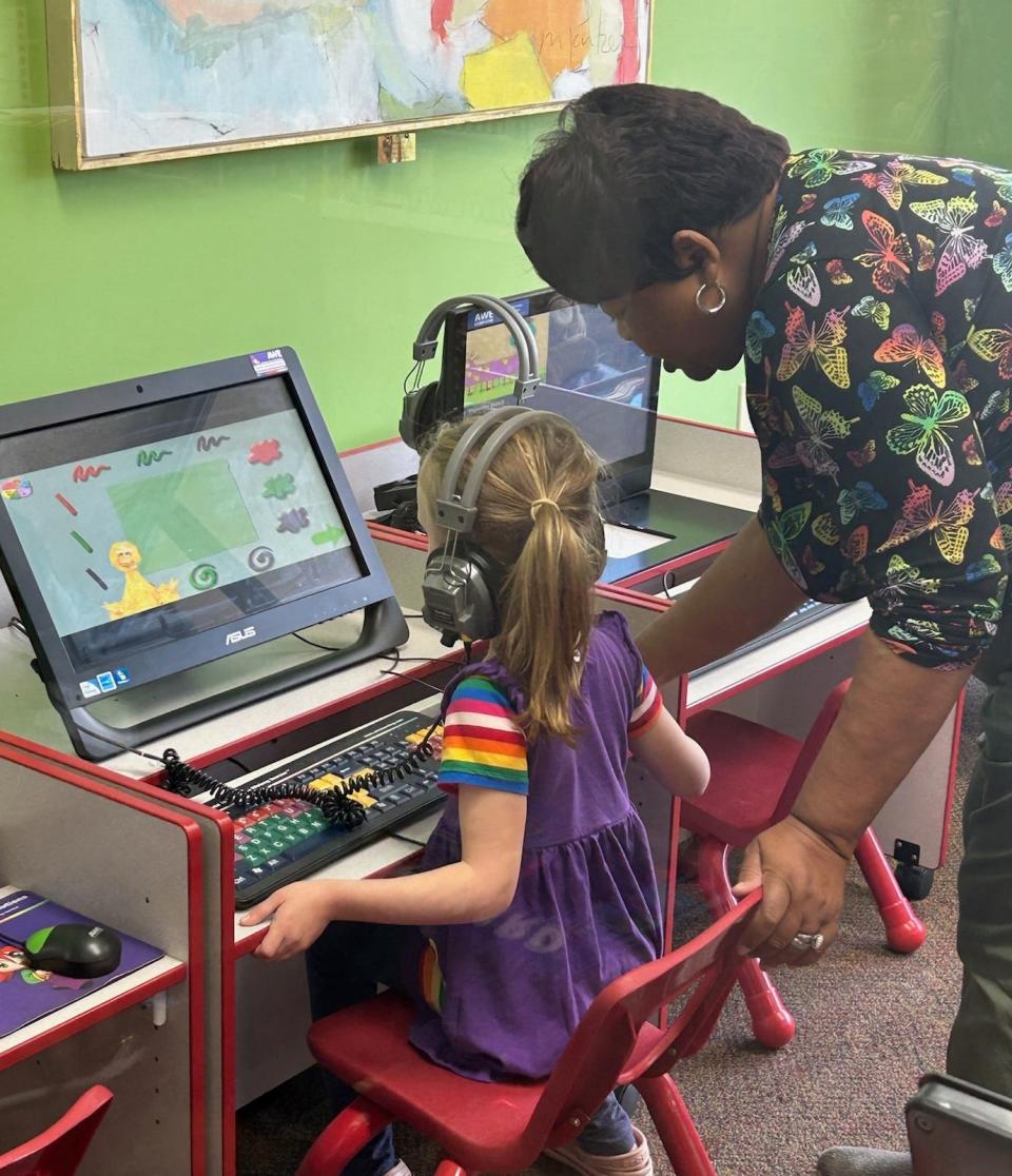 Angela Jones, the Louisville Library branch Circulation Desk Clerk, helps a young patron access fun learning activities on one of the branch's many computers.