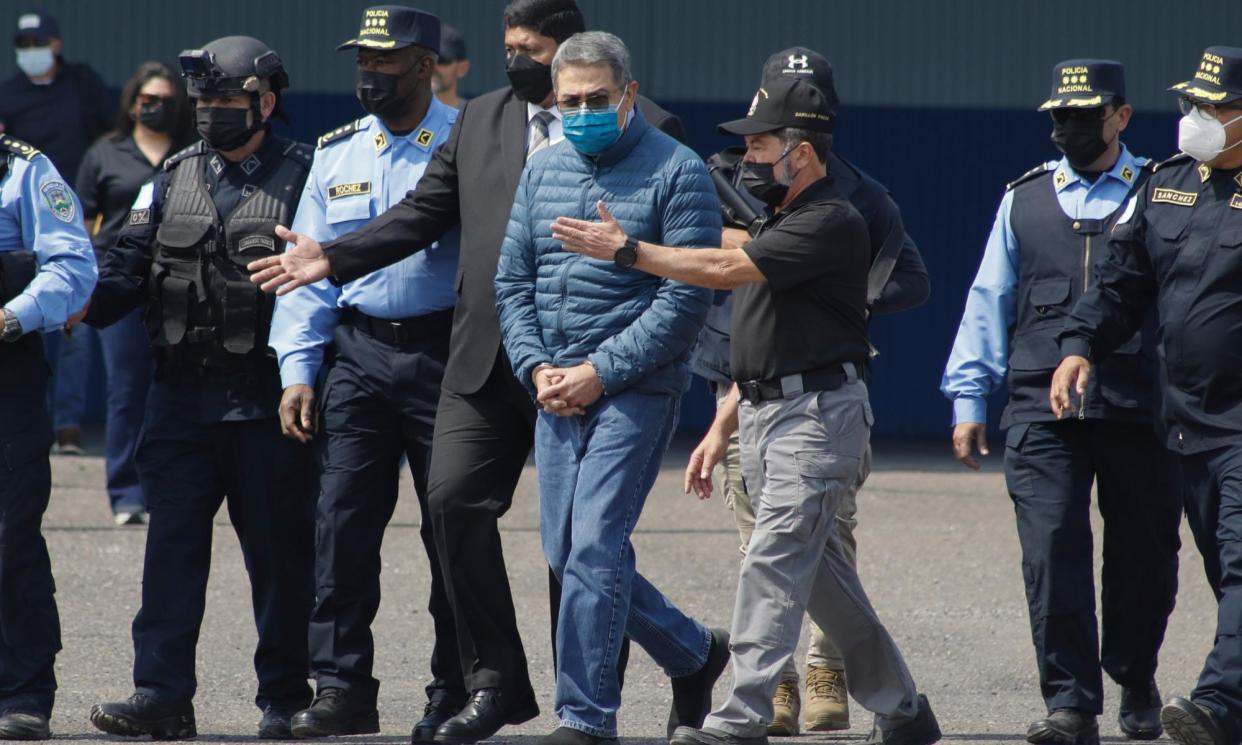 <span>The former Honduran president Juan Orlando Hernández, center, is taken in handcuffs to a waiting aircraft in Tegucigalpa as he is extradited to the United States on 21 April 2022.</span><span>Photograph: Elmer Martinez/AP</span>