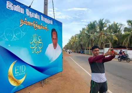 A boy takes a selfie in front of a poster of former Eastern Province governor Hizbullah in Kattankudy