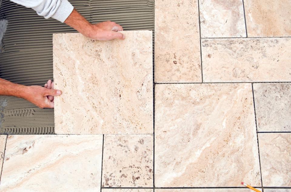 Natural stone tile flooring being installed in a bathroom