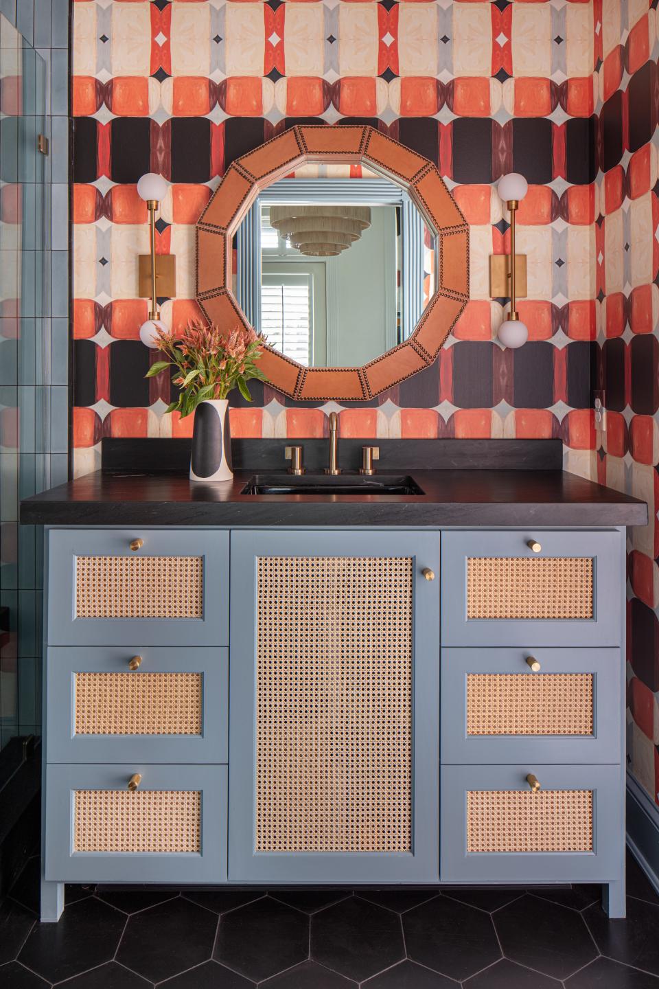 A warm orange Ford B wall covering by Lindsay is named for one of her sons and encompasses the boys’ bathroom. Accent pattern is incorporated subtly through the black hexagonal Clé tile and the natural cane webbing on the custom blue vanity. The brass wall sconces are by Tech Lighting and the studded camel leather mirror is by Made Goods.