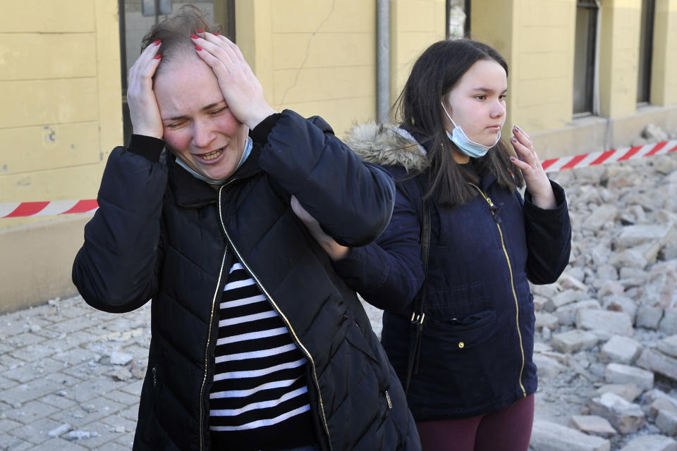 A woman reacts next to buildings damaged in an earthquake in Petrinja, Croatia, Tuesday, Dec. 29, 2020. A strong earthquake has hit central Croatia and caused major damage and at least one death and 20 injuries in a town southeast of the capital Zagreb. (AP Photo)