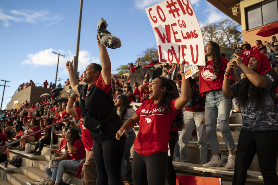 Lahainaluna High School football fans cheer for the junior varsity team at Sue D. Cooley Stadium, Saturday, Oct. 21, 2023, in Lahaina, Hawaii. Lahainaluna’s varsity and junior varsity football teams are getting back to normal since the devastating wildfire in August. (AP Photo/Mengshin Lin)