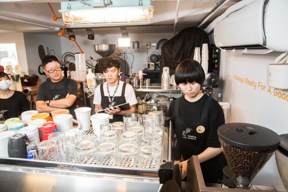 何炳霖（左二）在考試現場觀察吧台手沖煮咖啡，確保品質穩定。