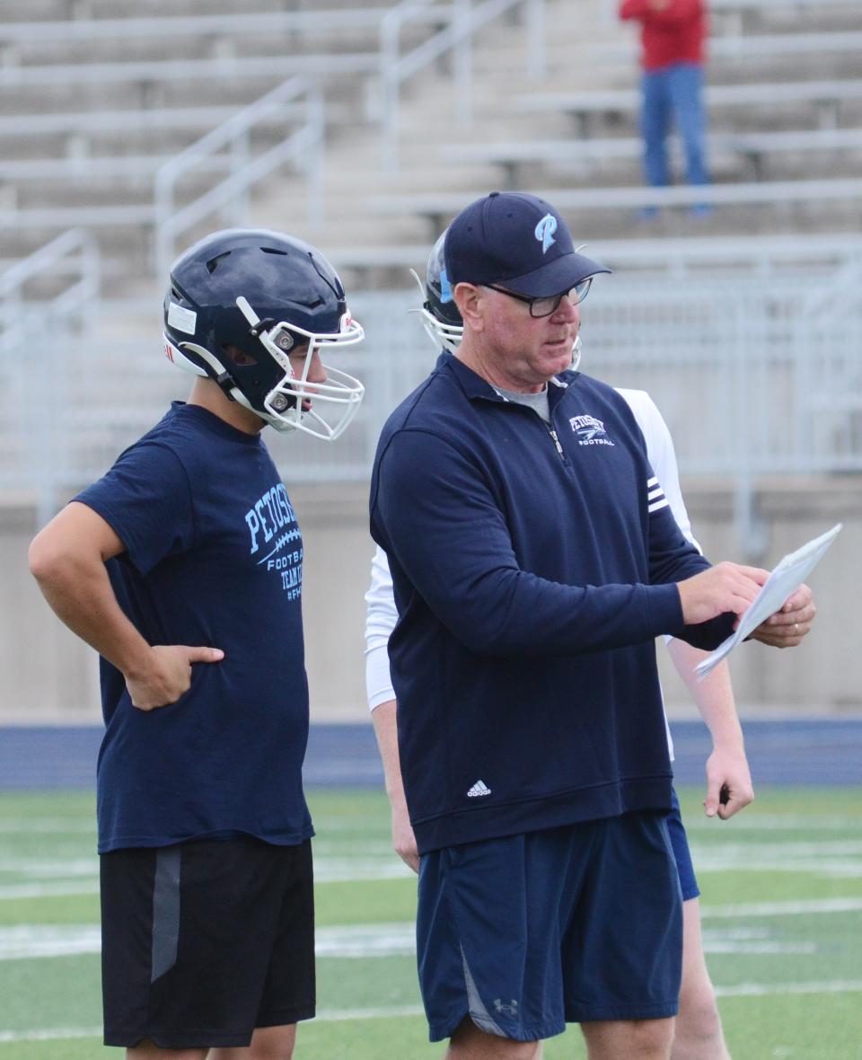 Longtime Petoskey assistant Mike Loper goes over a play with linebacker Tyler Dohm on Monday.