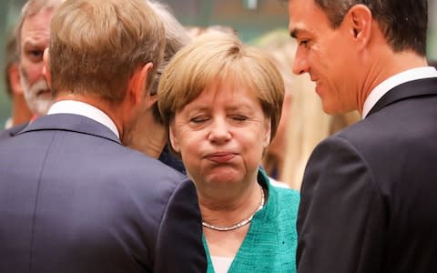 Germany's Chancellor Angela Merkel (C) reacts as she speaks with European Council President Donald Tusk (L) and Spain's Prime Minister Pedro Sanchez during an European Union leaders' summit - Credit: AFP