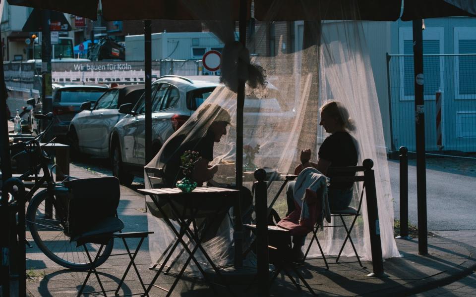 A couple sits in a cafe covering with masquito net to protect the wasp and also keep social distance in Cologne, Germany - NurPhoto