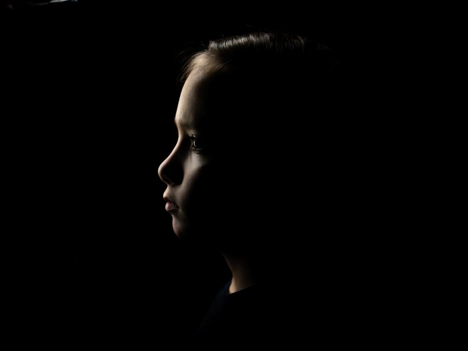 A profile shot of a child staring into darkness