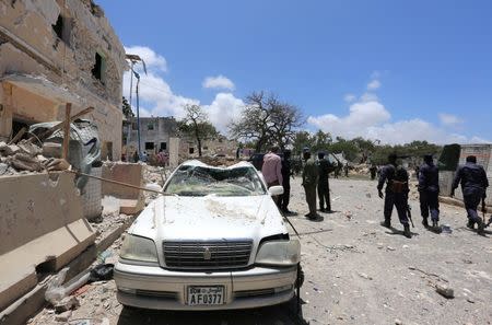 Somali government forces walk past a car destroyed as they arrive to secure the scene of a car bomb claimed by al Shabaab Islamist militants outside the president's palace in the Somali capital of Mogadishu, August 30, 2016. REUTERS/Feisal Omar