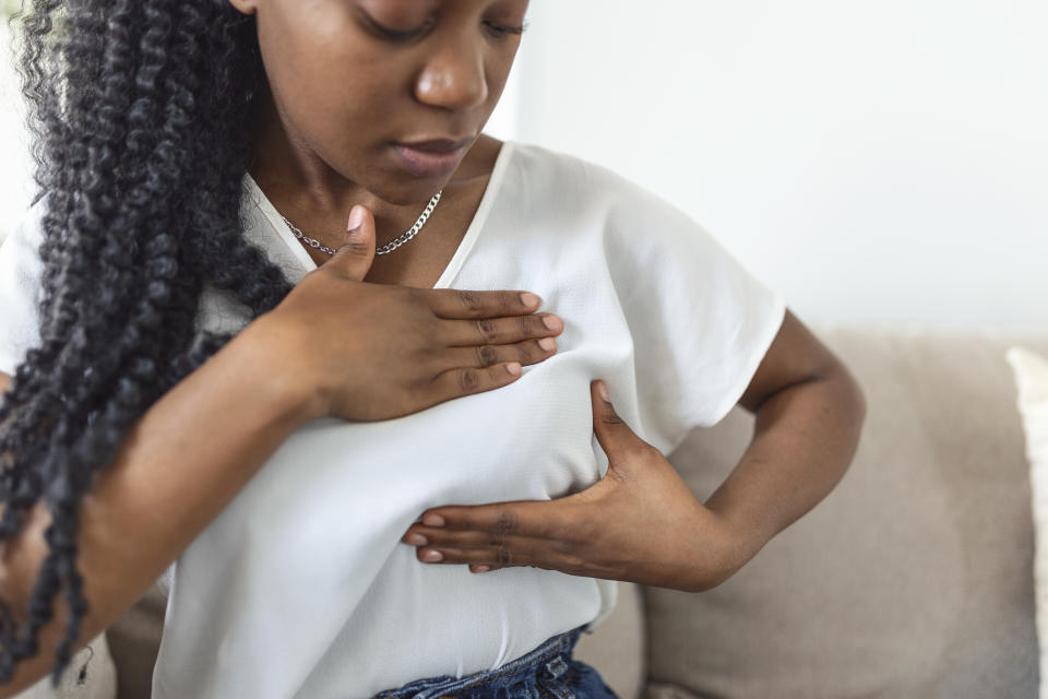 Young African American woman palpating her breast by herself that she concern about breast cancer. Healthcare and breast cancer concept