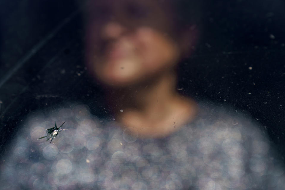 A crack in the windshield from a piece of shrapnel after a recent rocket attack is visible as Anna Kolesnyk sits in the passenger seat waiting for her husband to finish delivering bread to a store near the front line in Dyliivka, Donetsk region, eastern Ukraine, Saturday, Aug. 20, 2022. Since the attack, Kolesnyk now accompanies her husband to front-line villages to be with him instead of at home should something terrible happen. (AP Photo/David Goldman)