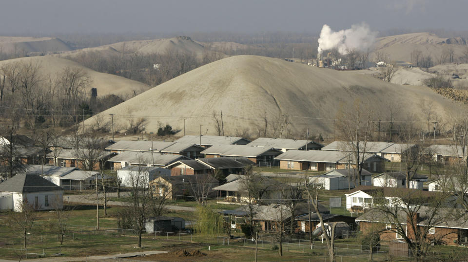 FILE - This April, 6, 2008 file photo shows Picher, Okla., nestled among huge lead-laced piles of rock. In eastern Oklahoma’s Tar Creek mining district, waterways are devoid of life and elevated lead levels persist in the blood of children in 2019, despite a two-decade effort to clean up lead and zinc mines. More than $300 million has been committed since 1983, but only about 2 percent of the impacted land has been reclaimed and contaminated water continues to flow. (AP Photo/Charlie Riedel, File)