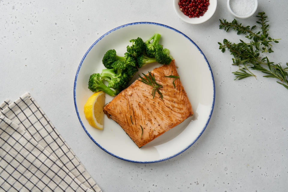 Baked fish and vegetables. Grilled fried salmon, broccoli, paleo, keto, lshf, fodmap or dash diet. Mediterranean food with steamed fish. Oven dish, healthy concept, gluten free, clean eating, balanced food. White ceramic plate on gray table. Top view