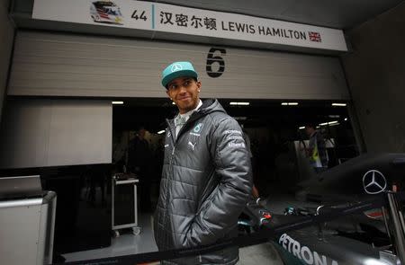 Mercedes Formula One driver Lewis Hamilton of Britain smiles as he walks at the team garage during the second practice session of the Chinese F1 Grand Prix at the Shanghai International circuit, April 18, 2014. REUTERS/Carlos Barria