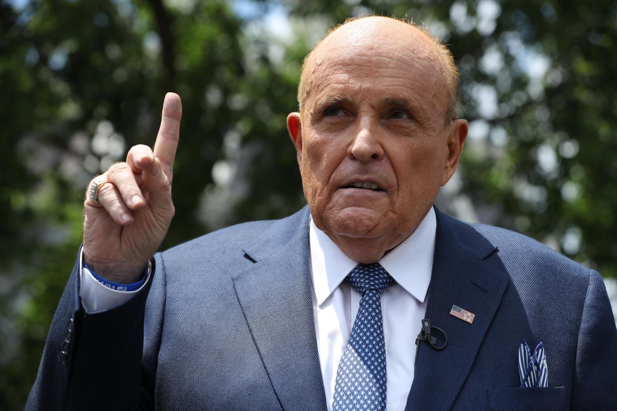 Rudy Giuliani holds his pointer finger in the air.