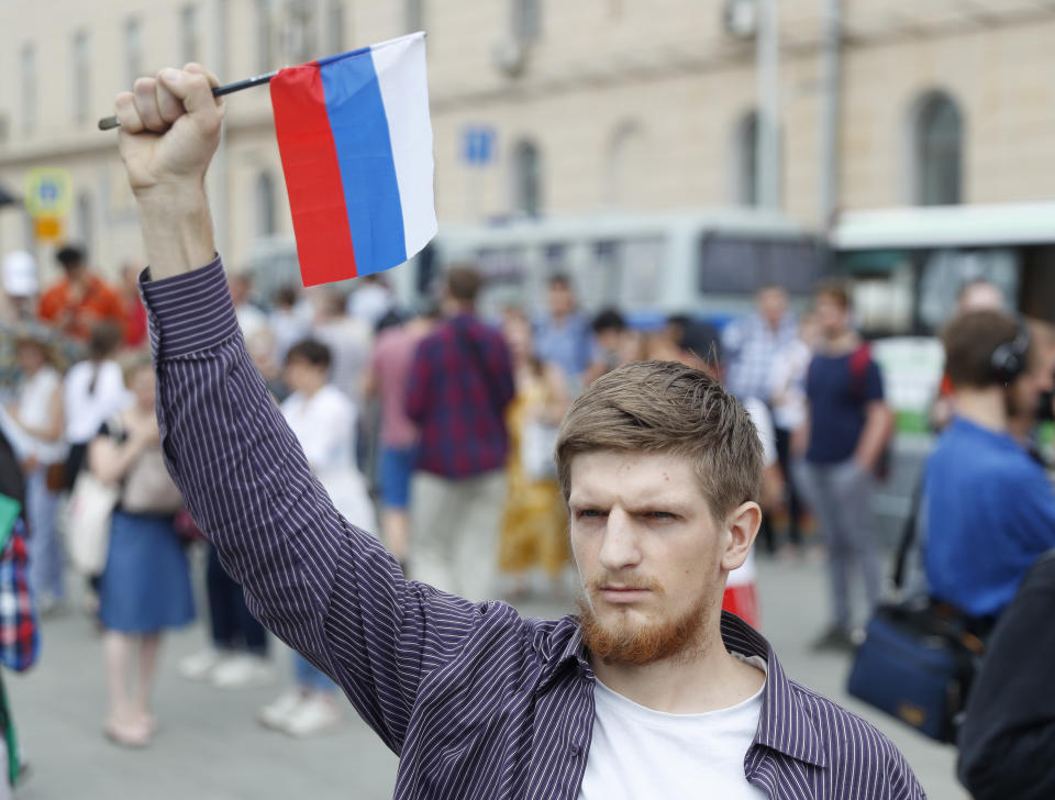 Young mans holds a state flag as supporters of Russian investigative journalist Ivan Golunov and other protesters gather to attend a march in Moscow, Russia, Wednesday, June 12, 2019. (AP Photo/Pavel Golovkin)