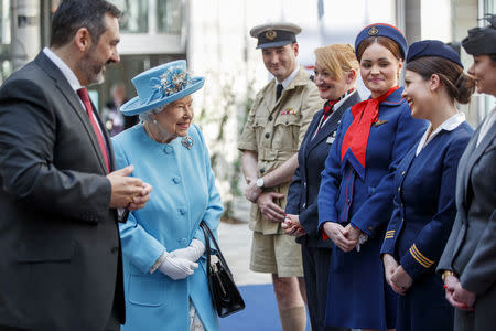 Britain's Queen Elizabeth is accompanied by Chief Executive of British Airways, Alex Cruz, as she meets employees dressed in heritage uniforms during her visit to the headquarters of British Airways, as British Airways mark their centenary year, in Heathrow, west London, Britain May 23, 2019. Tolga Akmen/Pool via REUTERS