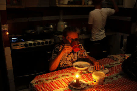 Juana Guerrero uses a candle to illuminate the table while she dines during a blackout in San Cristobal, Venezuela March 13, 2018. Picture taken March 13, 2018. REUTERS/Carlos Eduardo Ramirez