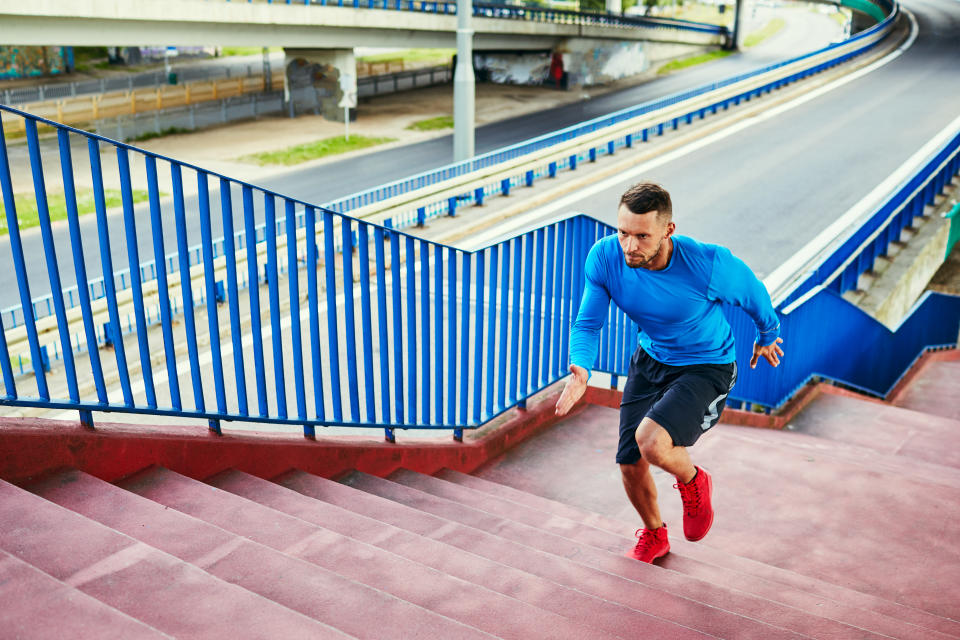 Athletic man doing interval training running on stairs in urban setting